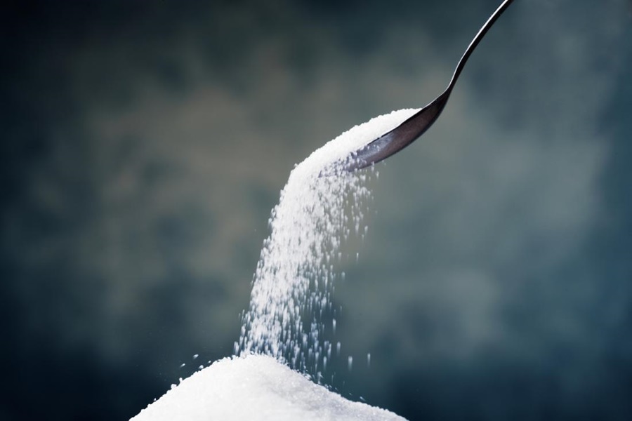 spoon spilling sugar into a pile