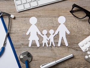 paper cut out of family in front of a laptop and stethoscope